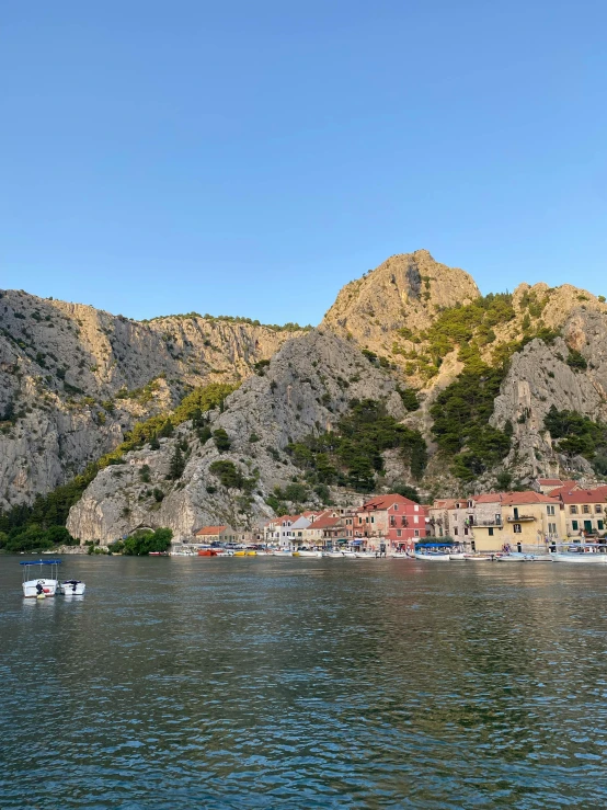 several small boats on a large lake in front of mountains