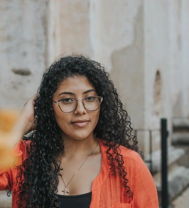 a woman with long curly hair wearing glasses