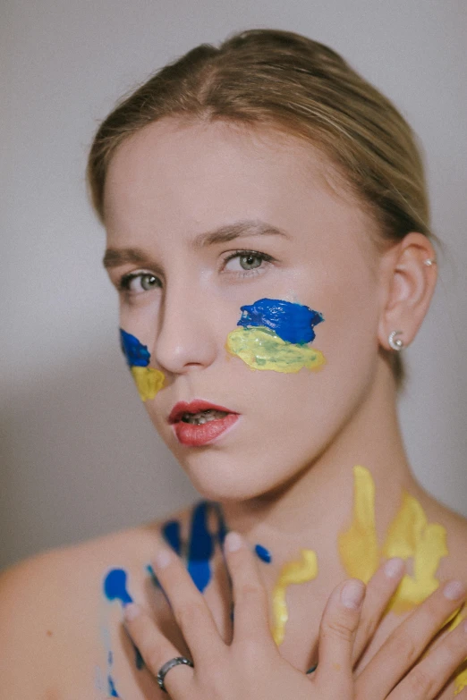 a girl with face painted in a yellow blue and white paint