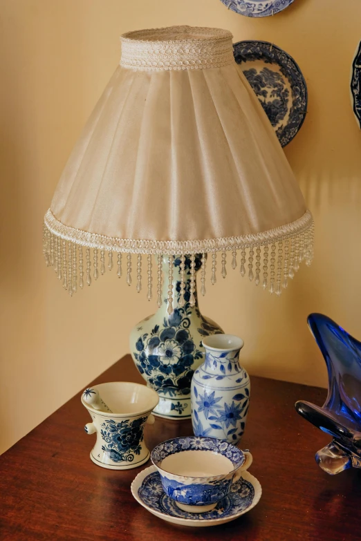 a blue and white lamp on a table with china