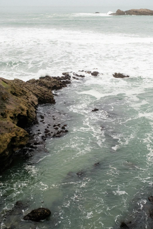 a man on a boat on the water near a rocky shore