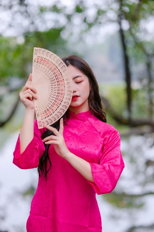 young asian woman with pink clothing holding umbrella in a park