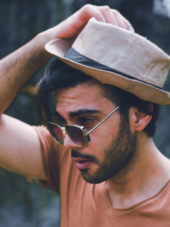 a man is posing in the sunlight with a hat on