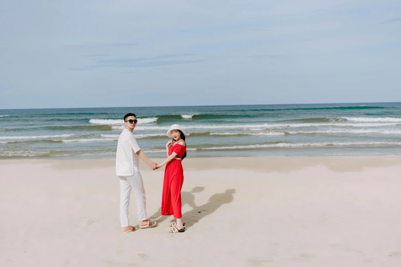 a man and woman hold hands while standing on a beach