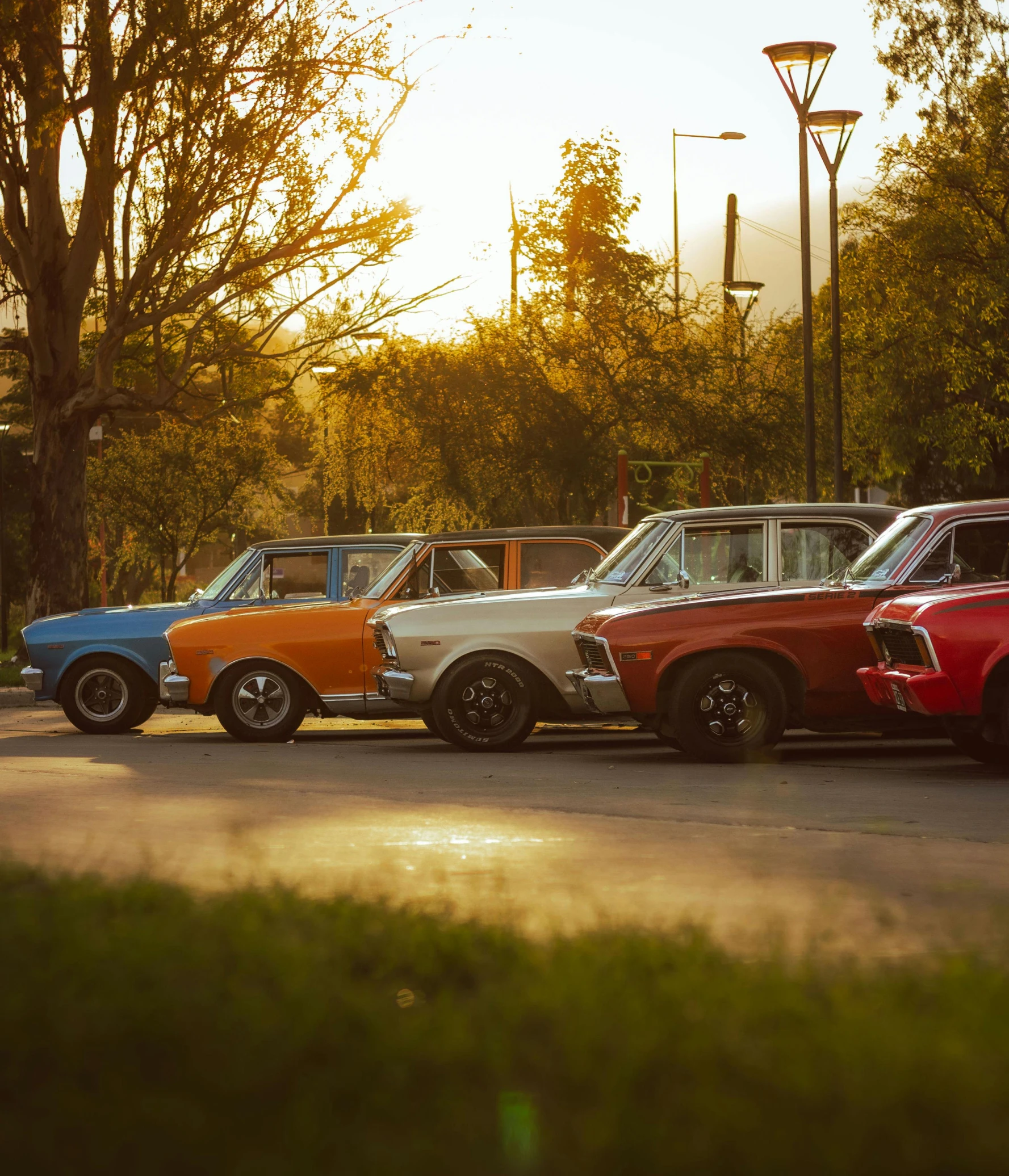 the group of three different colored classic cars is parked