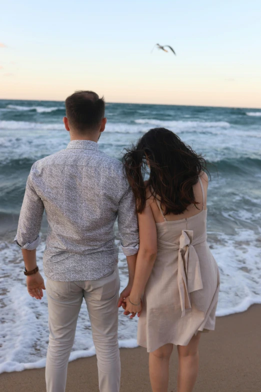 a couple holding hands looking out to sea