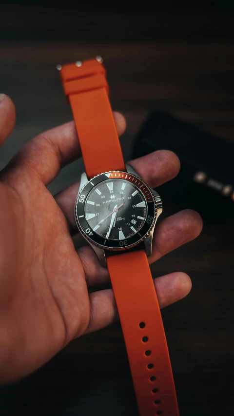 a man holding onto an orange strap for his watch