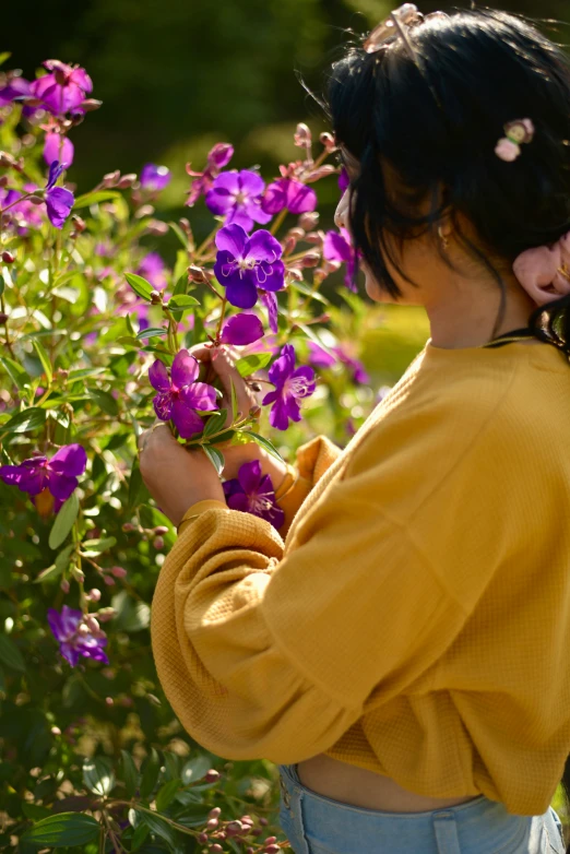 a woman in yellow shirt by purple flowers