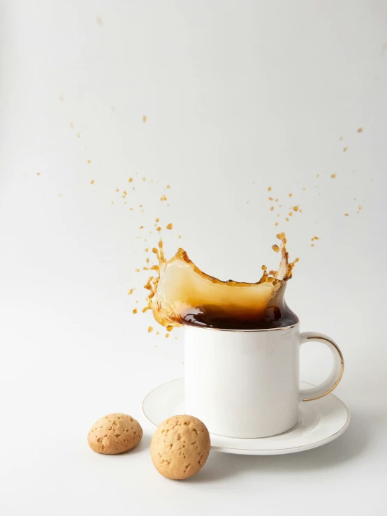 a cup of coffee with liquid splashing out of the top