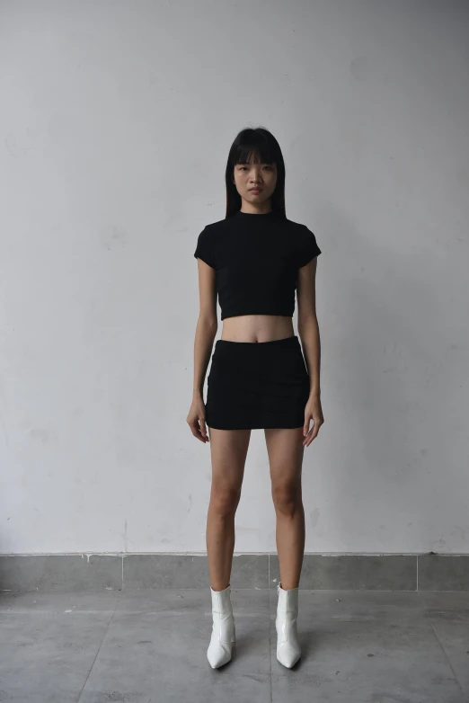 a model wears a black shirt and a skirt with high heels
