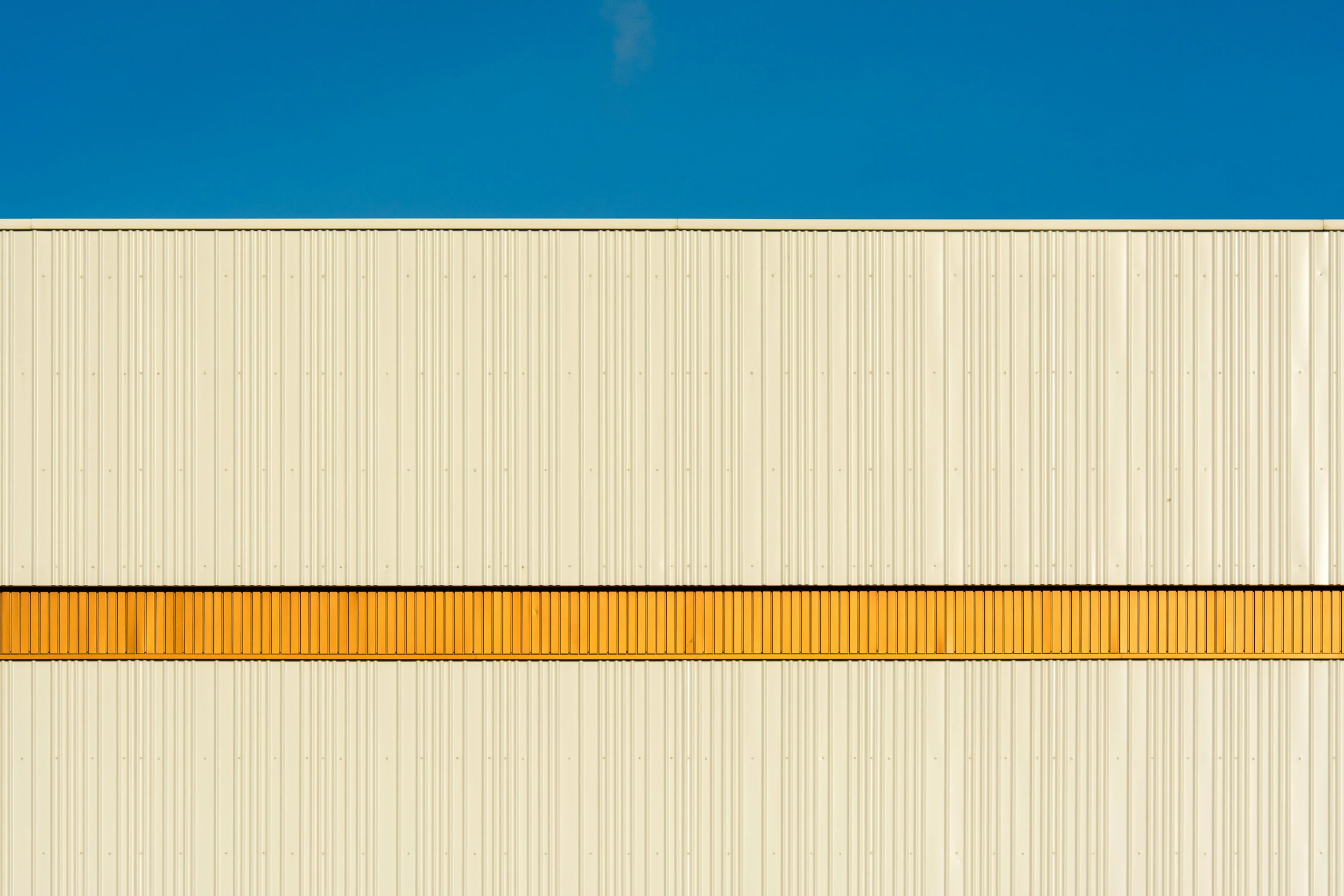 an angled s of a building wall and a yellow strip