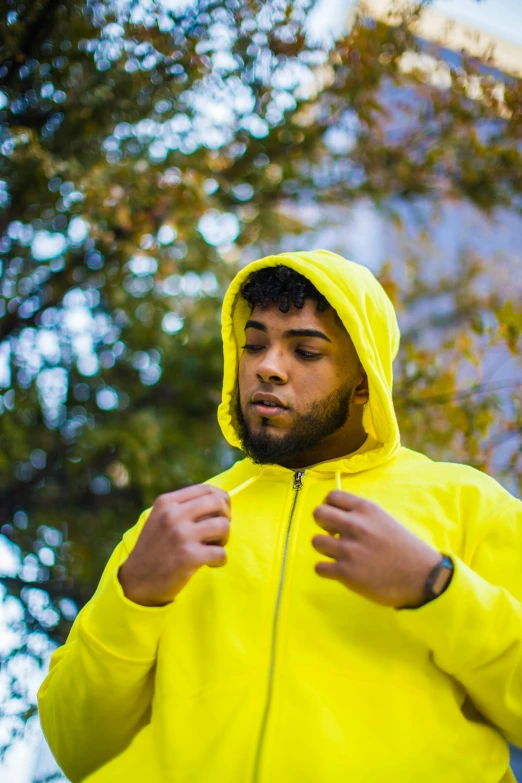 man in yellow hoodie standing outside with trees in background
