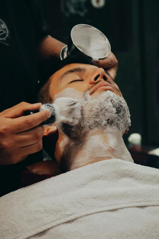 a man shaving the face of another man with a hairdryer