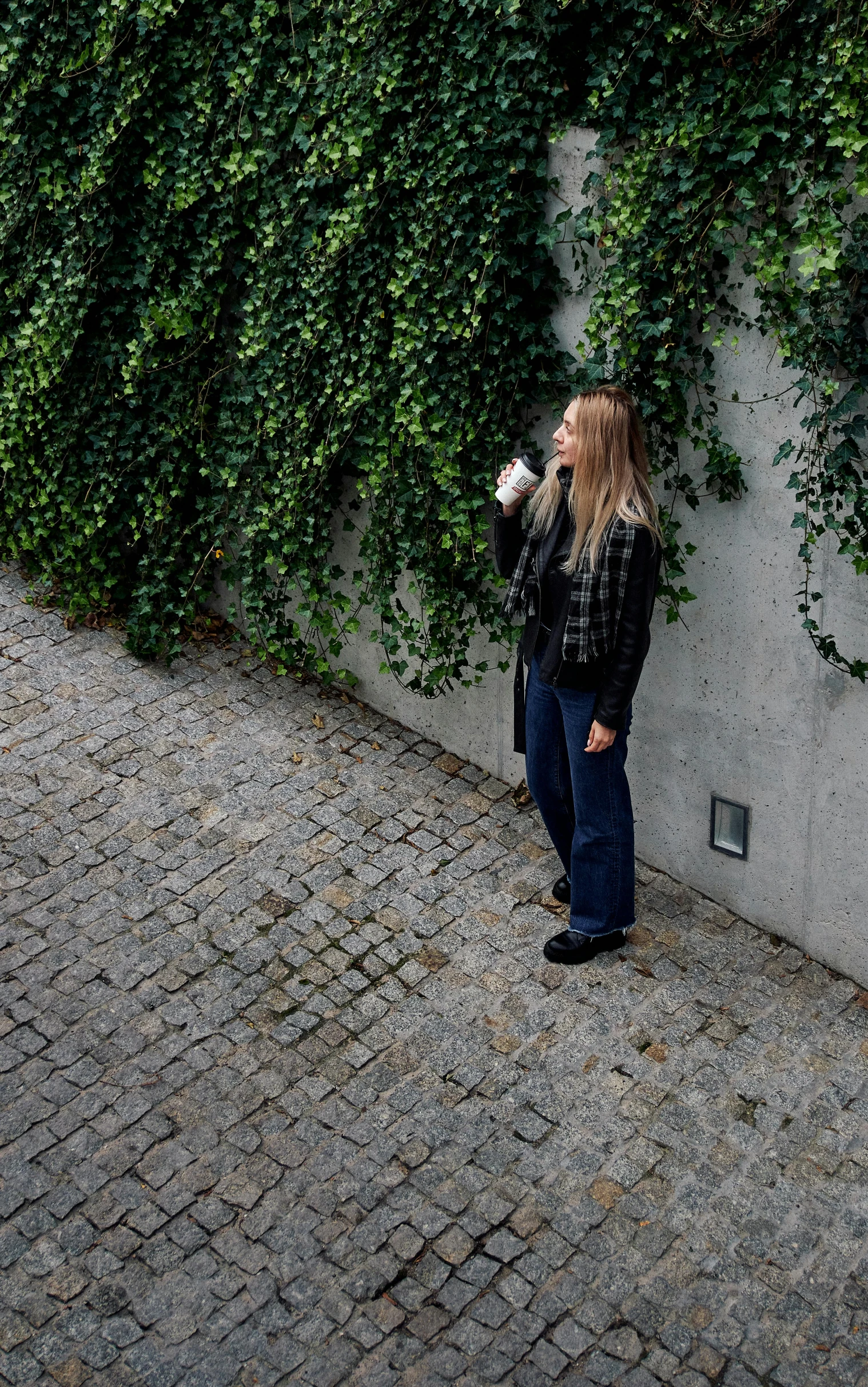 a woman is leaning on the wall drinking coffee