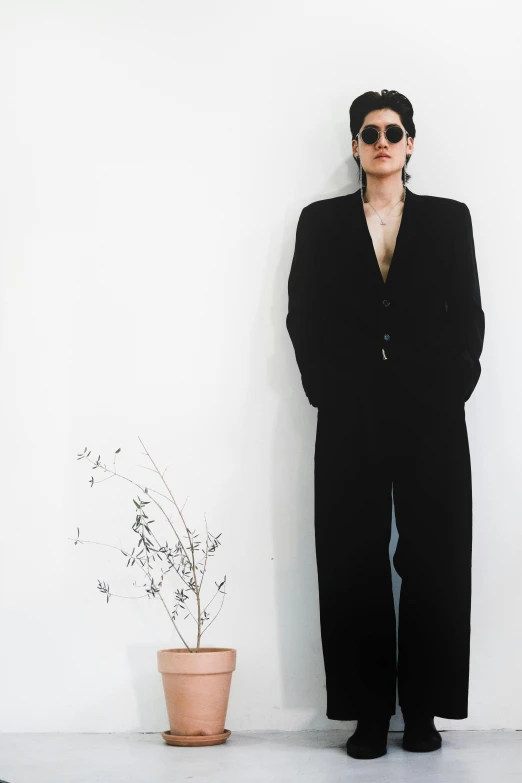 a man wearing shades and posing in front of a plant