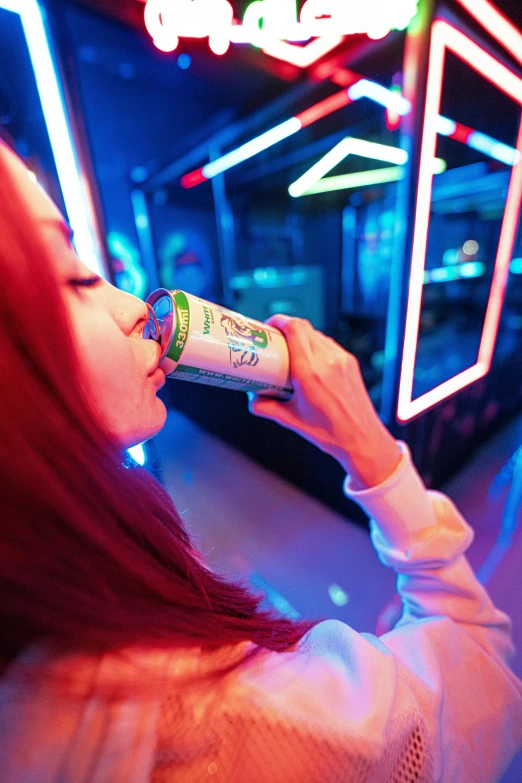 the girl drinks from a drink bottle at the neon bar