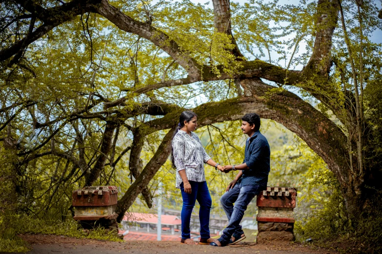 two men in blue jeans standing next to trees