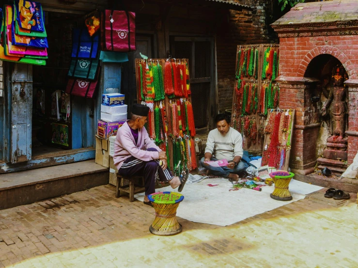 people sit outside of a market with colorful items