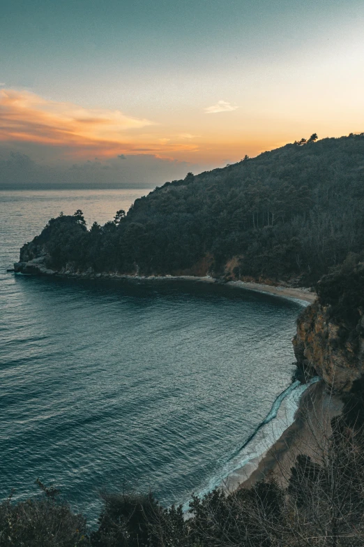 a view of some blue water and a hill at sunset