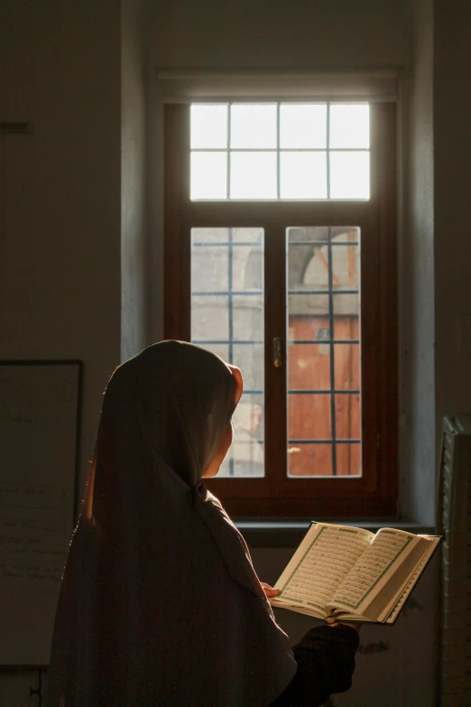 woman sitting in a room holding an open book