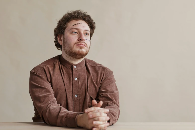 a man with his hands crossed is sitting down looking up