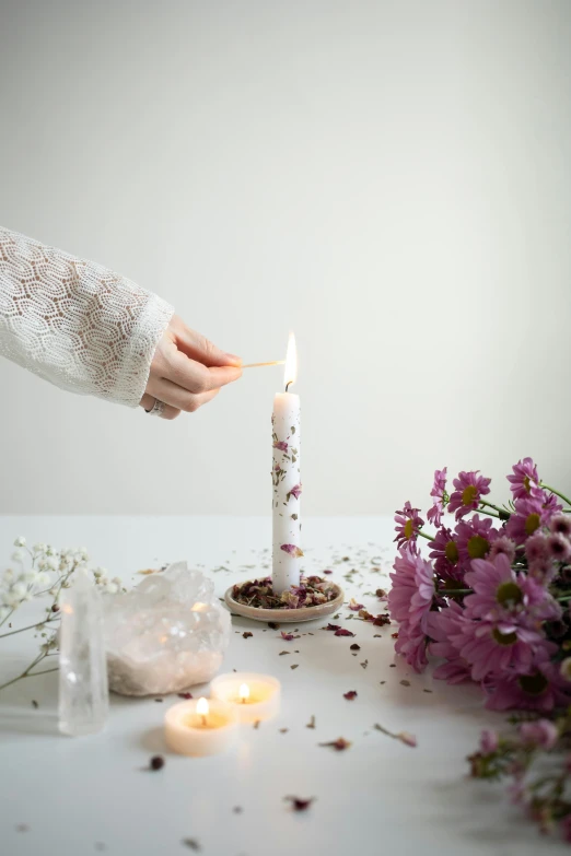 someone is lighting a candle on top of a table with flowers