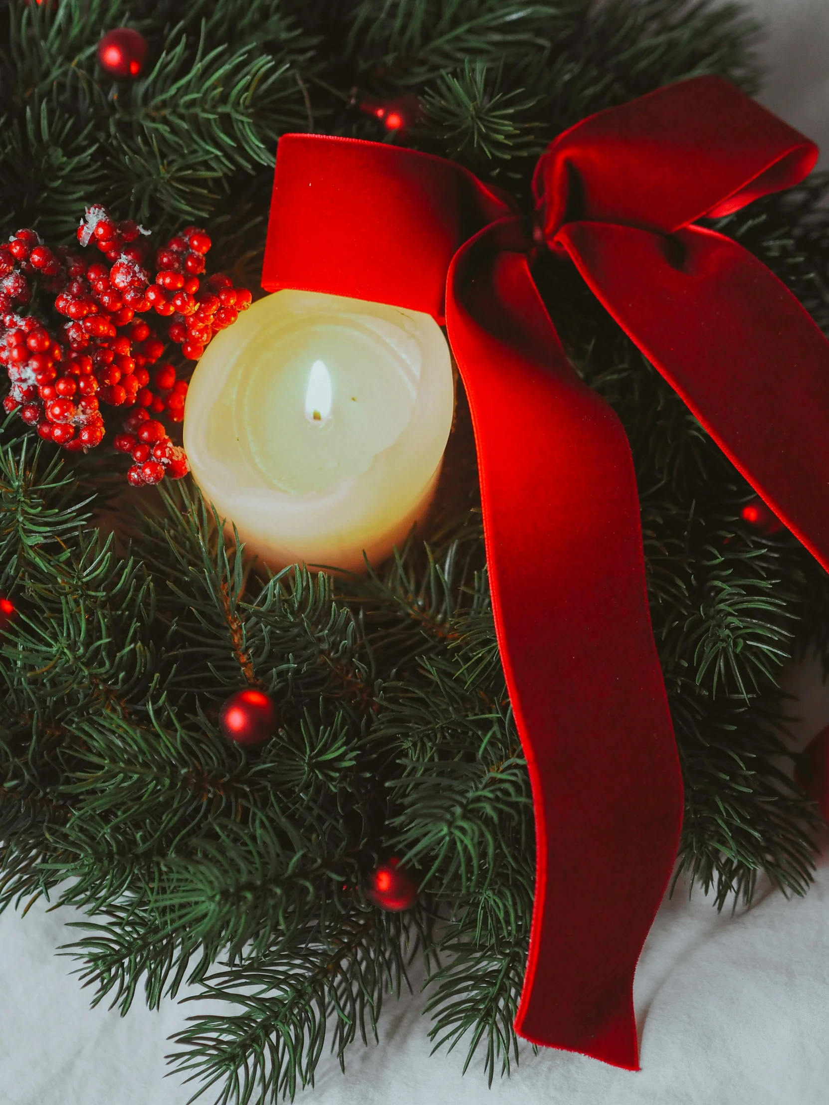 candle with red ribbon and holly and other holiday items