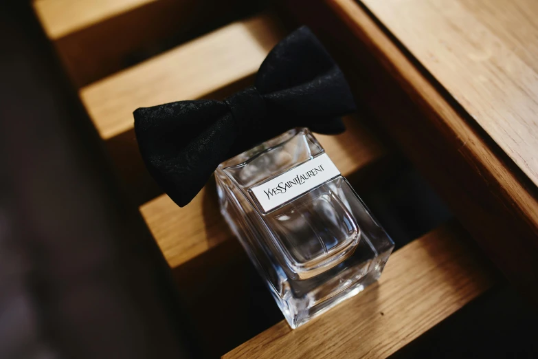 a glass perfume bottle and black bow tie