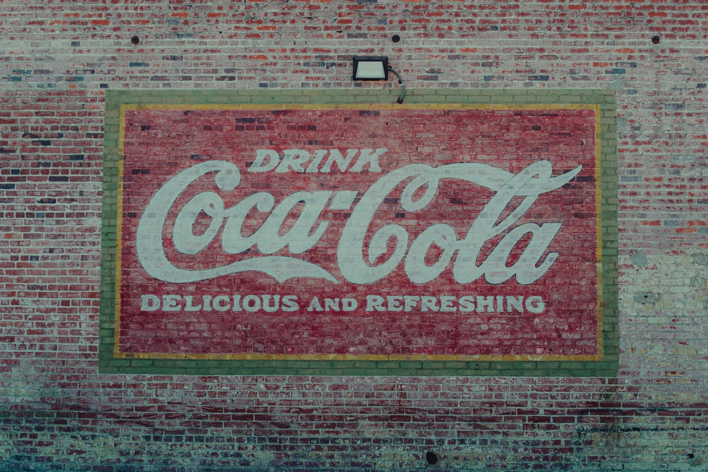 an old sign on the side of a building that says, drink coca - cola delicious and refreshing