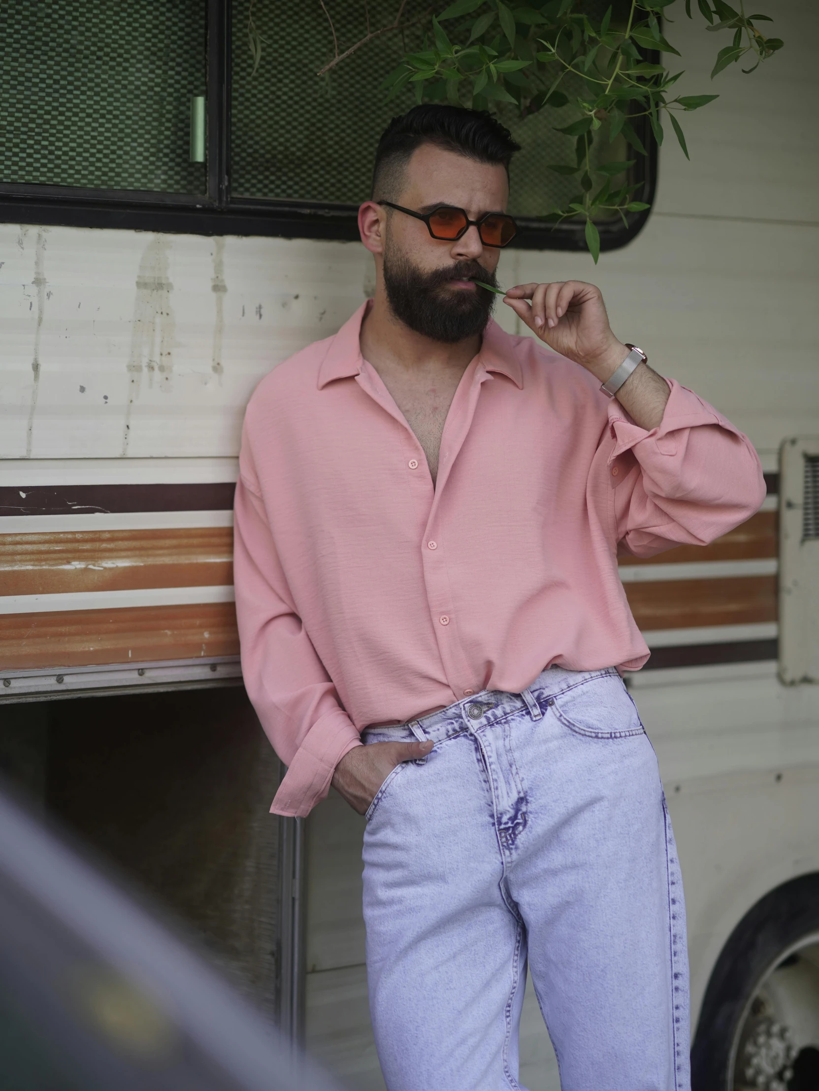 a man wearing blue jeans leaning on his rv