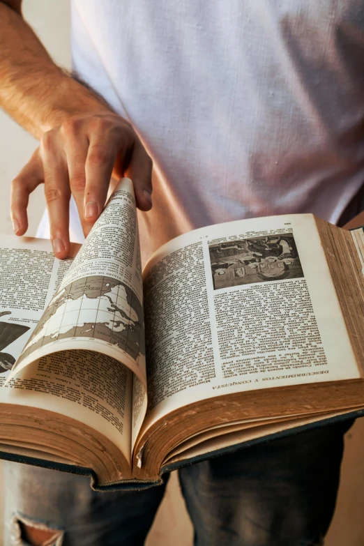 someone standing behind a book, pointing it to the page