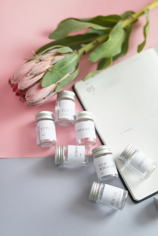 six small glass jars sitting next to a notebook and flowers