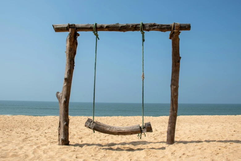 the empty beach has a swing and nch for swinging