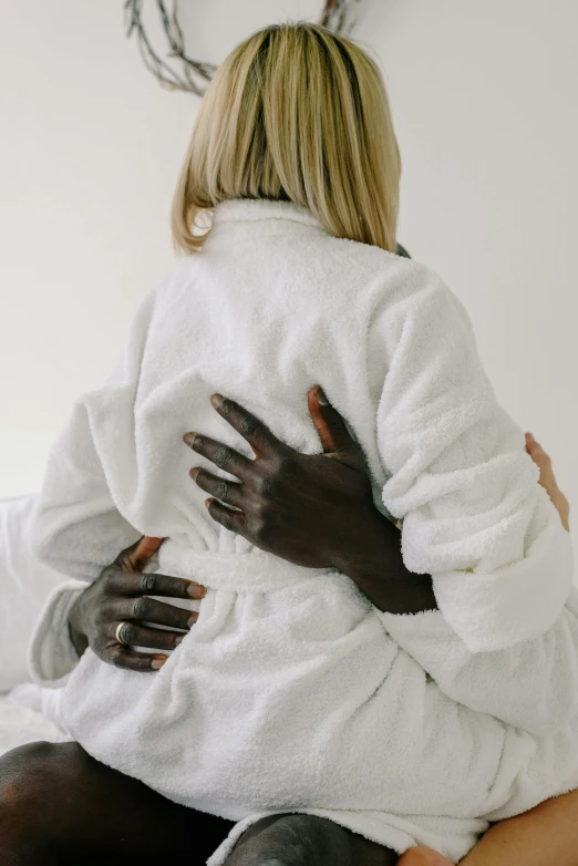 a woman in a white robe is hugging a man