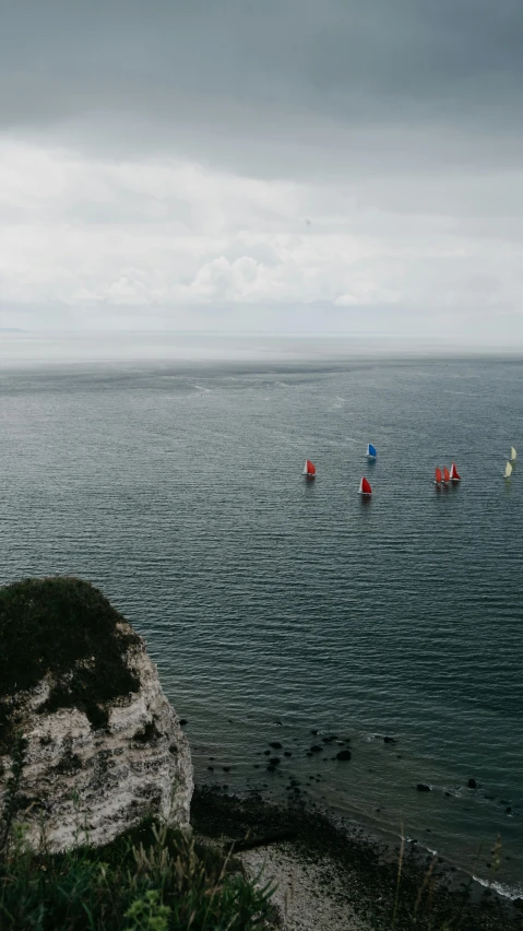 two boats floating on the ocean on top of a large rock