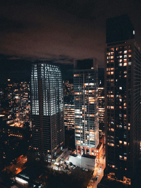 a night city with skyscrs and many buildings lit up