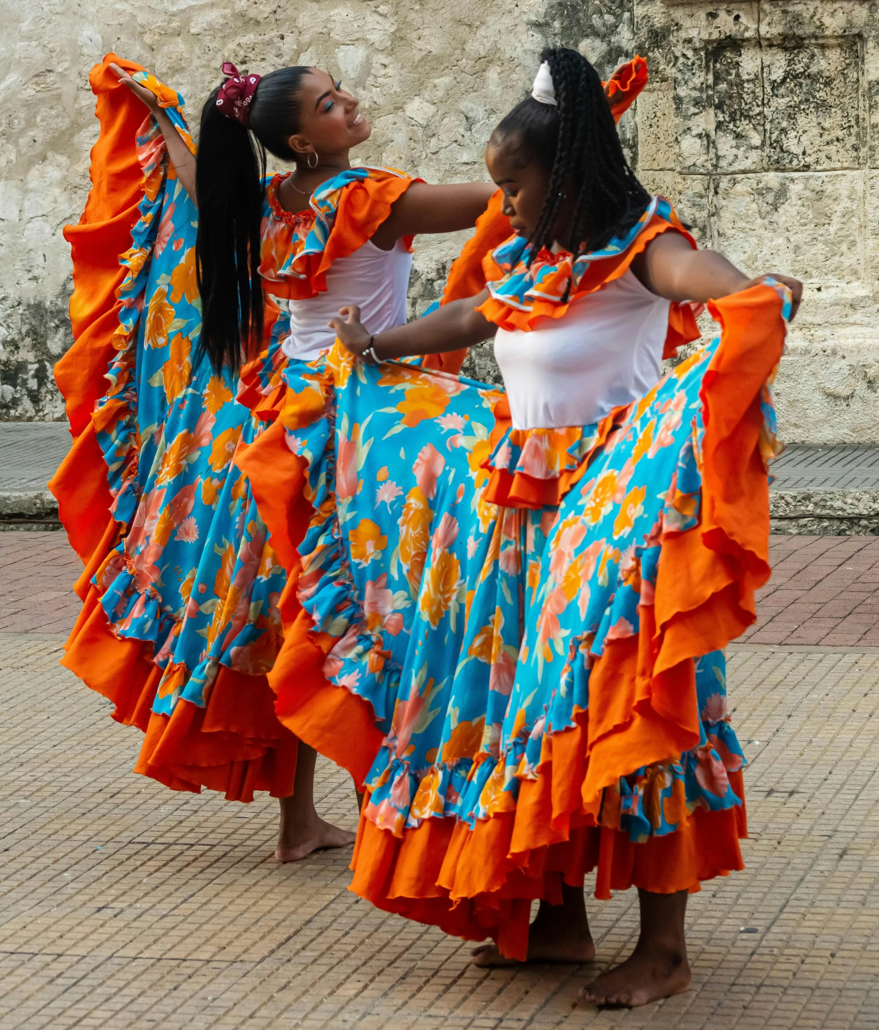 two young women wearing colorful dresses dancing