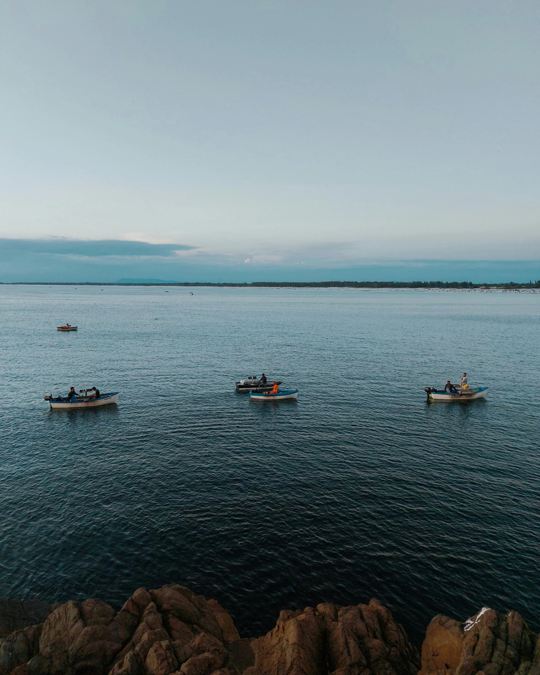 four boats floating on the water near the shore