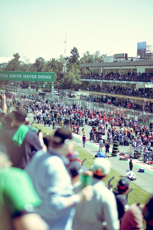 a crowd of people gathered at a race in front of a stadium