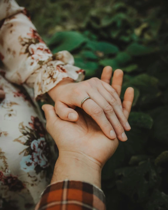 two people holding hands in a wooded area