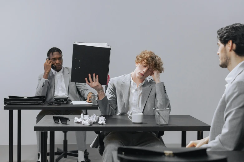 some people sitting at a table talking with one holding a book