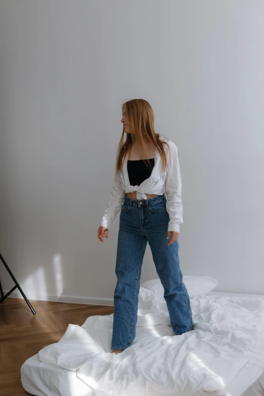 a girl in a white shirt is standing on a bed