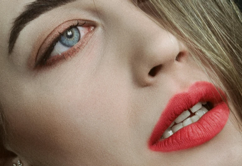 a woman with red lips and white teeth is looking off to the side