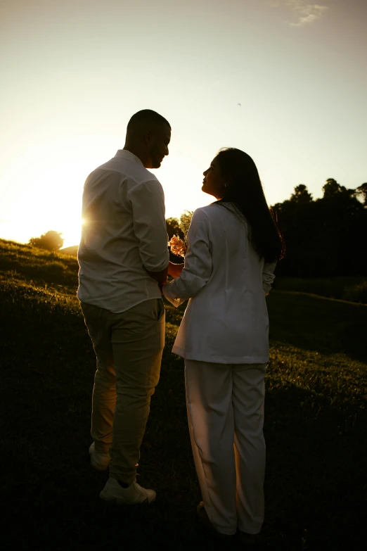 a man and woman holding hands while standing on top of a grass field