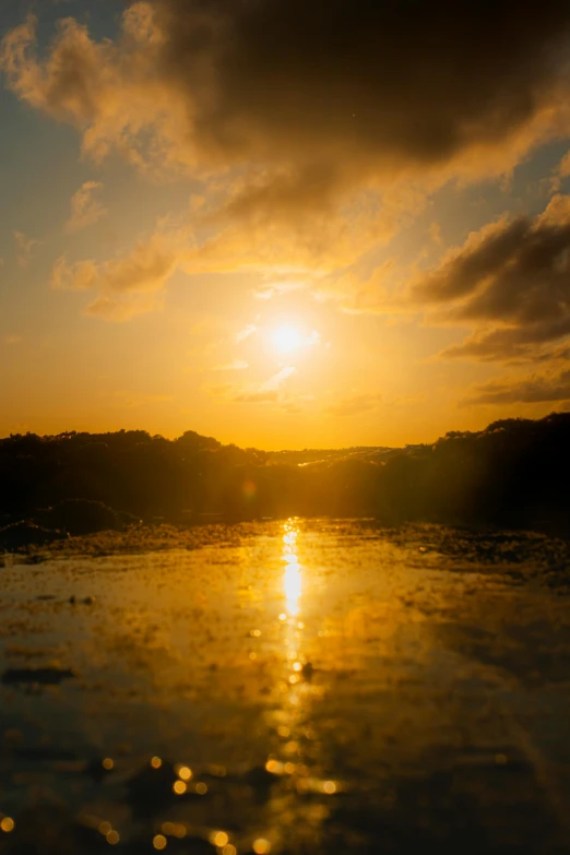 the sun is setting over the lake, reflecting on the water