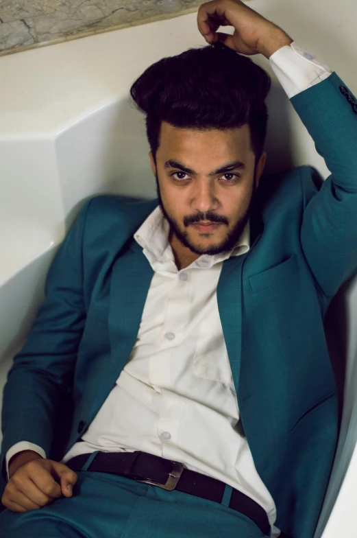 a man laying down in a bathroom with a beard