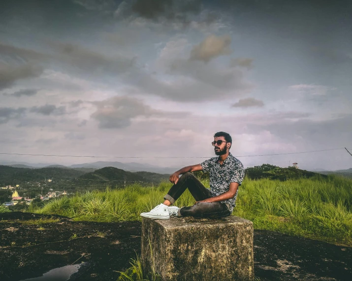 a man sitting on top of a wooden stump next to lush green grass