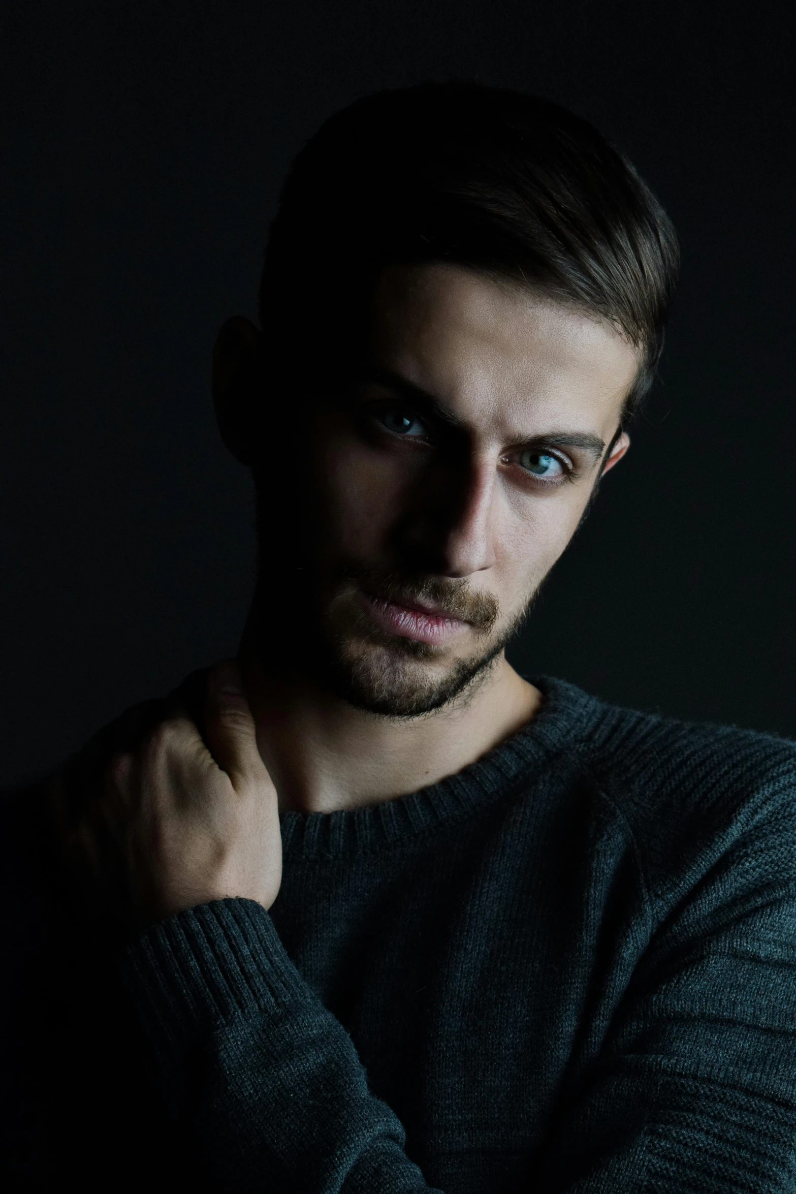 a man in black shirt and dark background with arms crossed