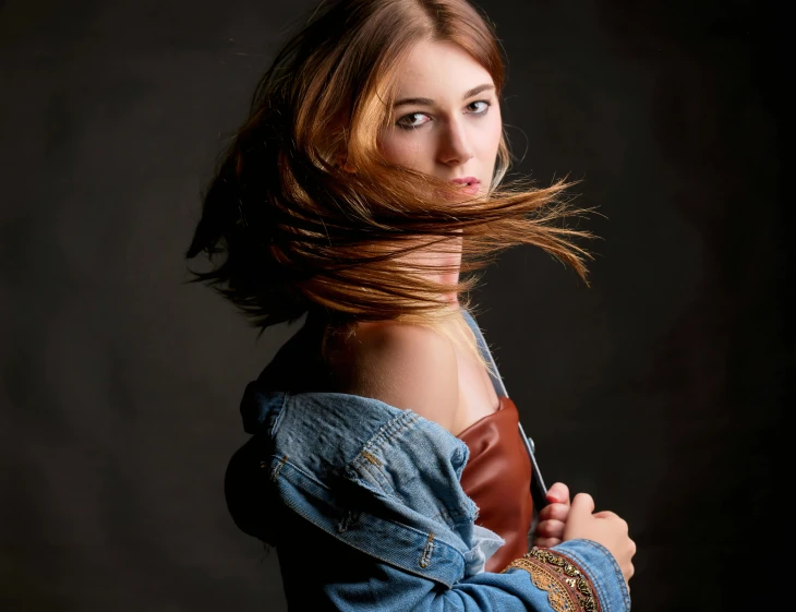 a woman holding a leather handle in one hand and looking to her left with a back lit area in the middle