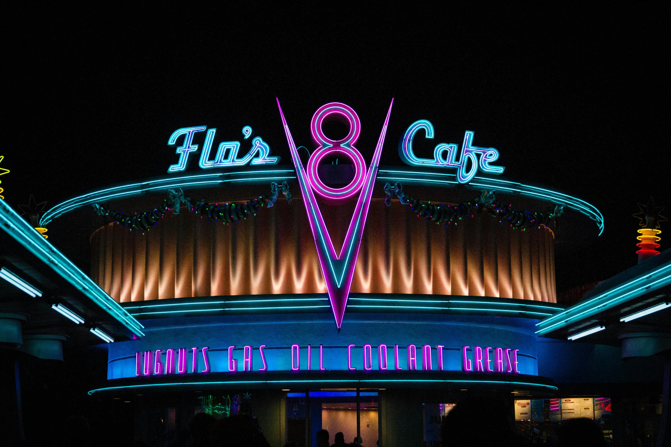 people walk along the night in front of a large building